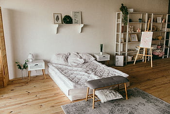 Spacious modern bedroom with minimalist decor, featuring a low bed, wooden floors, and shelf storage. HD wallpaper