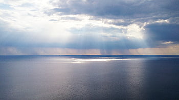 Captivating ocean view with sunrays breaking through clouds, creating a serene and calming effect. HD wallpaper
