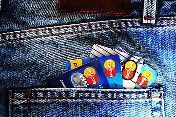 Close-up of a denim pocket with multiple credit cards, illustrating finance and fashion. HD wallpaper
