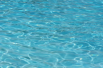 A vibrant turquoise water surface, showcasing clear ripples and captivating patterns. Perfect for summer themes. HD wallpaper