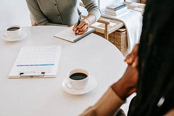 Two professionals engaging in a business meeting over coffee at an office. HD wallpaper