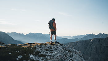 A lone hiker in Italy's mountains, embracing the serene landscape. HD wallpaper