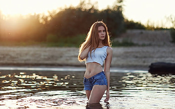 Polina Sterzhnykh, cropped, brunette, wading in the river, t top, denim shorts, long hair, sunset HD wallpaper