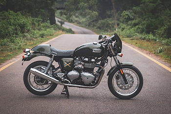 Captured on a tranquil road, a Triumph Thruxton motorcycle promises an adventurous ride. HD wallpaper