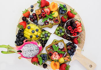 A vibrant and colorful platter of assorted fresh fruits including dragon fruit, berries, and sliced mango, perfect for healthy eating. HD wallpaper