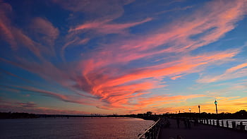 Stunning scenic view of a vibrant sunset over the Jersey City waterfront featuring colorful clouds and a calm river. HD wallpaper