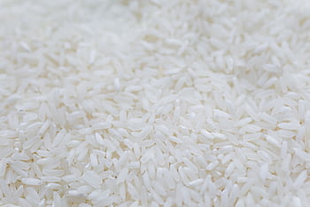 A detailed close-up shot of uncooked white rice grains, emphasizing texture and natural quality. HD wallpaper