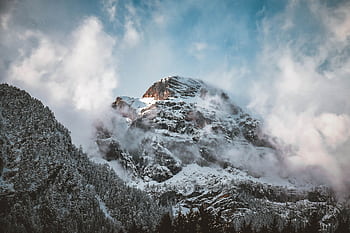 Majestic snowy peak surrounded by winter clouds in the Tyrolean Alps. HD wallpaper