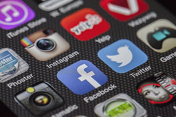 Close-up of various social media app icons on a smart screen. HD wallpaper