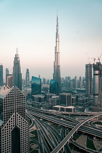 Aerial view of Dubai's skyline with Burj Khalifa and intricate highway system at sunset. HD phone wallpaper