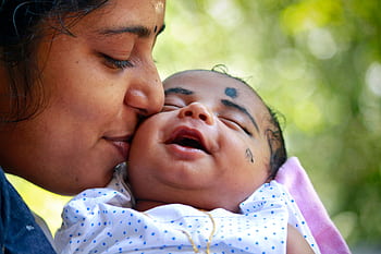 Heartwarming portrait of a mother kissing her smiling baby outdoors. HD wallpaper