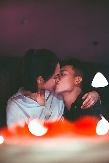A romantic kiss shared by an Asian couple, captured in a warm, intimate setting. HD phone wallpaper