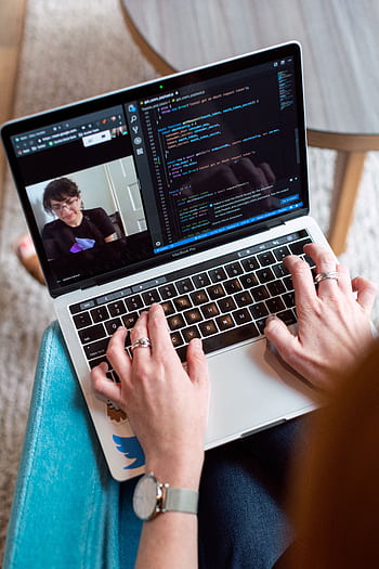 Person coding on a laptop during a video conference, showcasing remote work. HD phone wallpaper
