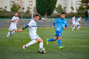 Football players in motion during a competitive soccer match on an outdoor field. HD wallpaper