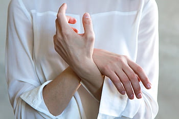 Elegant hands in a white shirt gently touching each other, symbolizing calm and tenderness. HD wallpaper