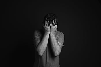 A grayscale portrait of a man covering his face, depicting emotion and mental health themes. HD wallpaper
