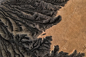 Drone capture of a barren, eroded geological formation in a desert, showcasing dramatic textures. HD wallpaper