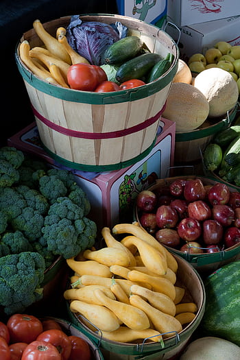 A vibrant display of fresh vegetables and fruits in baskets at a local market, showcasing healthy options. HD phone wallpaper