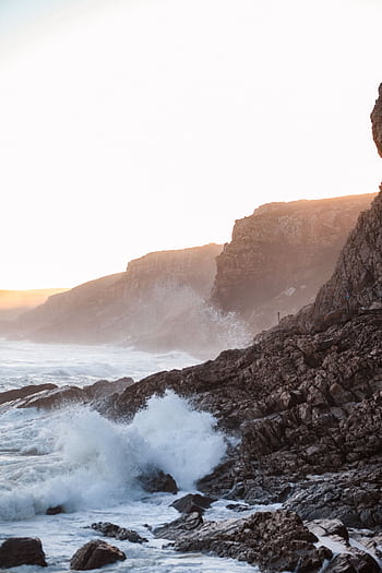 Capture the dramatic waves crashing against rocky cliffs at sunrise along South Africa's stunning coastline. HD phone wallpaper