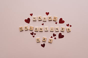 A festive Valentine's Day greeting with Scrabble tiles and red glitter hearts on a soft background. HD wallpaper