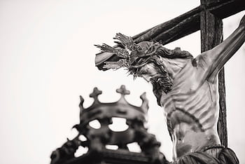 A dramatic close-up of a crucifix statue outdoors in Carmona, Spain, highlighting religious symbolism. HD wallpaper