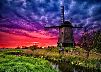Windmill at sunset, river, creek, nice, trees, water, sunset, windmill, sundown, mill, beautiful, grass, purple, green, clouds, nature, sky, lovely, stream HD wallpaper