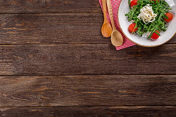 A delicious arugula salad with cherry tomatoes and pasta served on a rustic wooden table with space for text. HD wallpaper