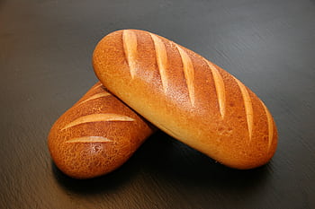 Close-up of two freshly baked loaves with crispy crust, ideal for food and still life graphy. HD wallpaper