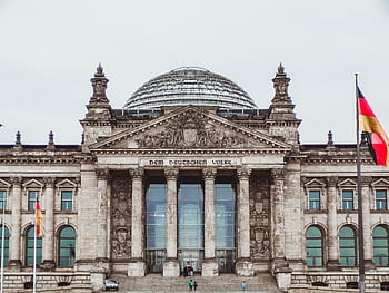Front view of the historic Reichstag Building in Berlin, Germany, featuring prominent German flags. HD wallpaper