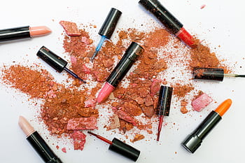 Colorful scattered makeup products including lipsticks and crushed powders on a white background. HD wallpaper