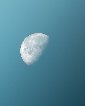 A vivid half moon captured in a serene blue sky, showcasing celestial beauty. HD phone wallpaper