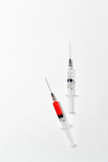 Close-up of syringes filled with red liquid on a white background, symbolizing medical treatment. HD phone wallpaper