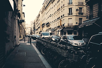 Busy European street with bicycles and cars lined under classic architecture. HD wallpaper