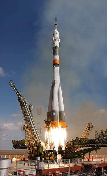 A powerful rocket launch lifting off with smoke and fire, ascending into a clear sky. HD phone wallpaper