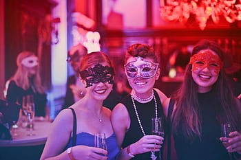 A vibrant masquerade party with happy guests wearing decorative masks and holding champagne glasses. HD wallpaper