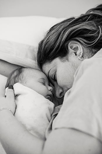 A tender moment of a mother cuddled with her sleeping baby, showcasing love and tranquility. HD phone wallpaper