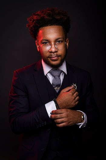Portrait of a stylish young man in a dark suit with eyeglasses, exuding confidence. HD phone wallpaper