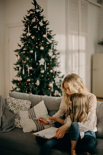 A mother and daughter enjoy a cozy moment by the Christmas tree indoors. HD phone wallpaper