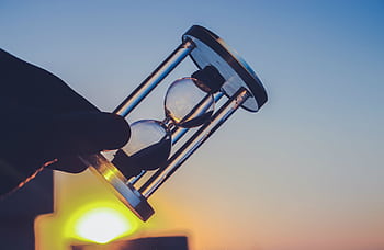 Silhouette of an hourglass held against a vibrant sunset sky in Syria. Time concept. HD wallpaper