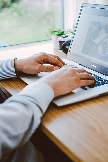 A man working on a laptop in a modern office setting. HD phone wallpaper
