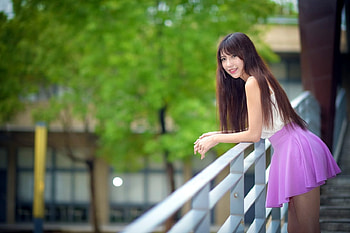 Cute Asian Model, violet mini skirt, leaning, Brunette, white top, trees, long hair, balcony railing HD wallpaper