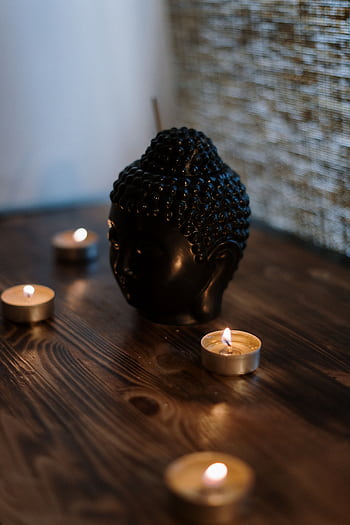 A serene setup with a Buddha head sculpture surrounded by soothing candlelight, perfect for relaxation. HD phone wallpaper