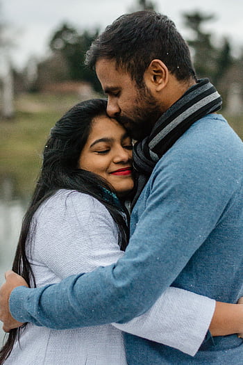 A loving couple embraces outdoors on a cool day, sharing a tender moment. HD phone wallpaper
