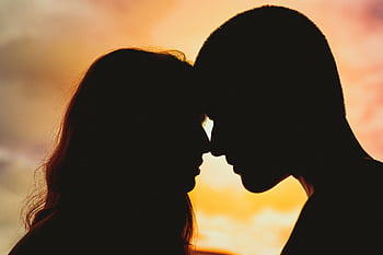 Silhouette of a romantic couple sharing an intimate moment at sunset. HD wallpaper
