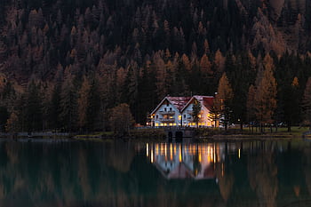Scenic autumn view of a lakeside house reflecting on calm waters at twilight. HD wallpaper