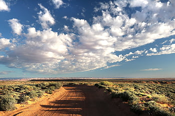 Beautiful desert scene with a dirt road and dramatic cloudy sky, perfect for travel and nature themes. HD wallpaper