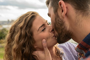 Close-up of a couple sharing a passionate kiss outdoors, capturing a moment of romance and affection. HD wallpaper
