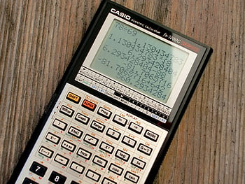 Close-up of a vintage Casio scientific calculator showing calculations on a wooden surface. HD wallpaper