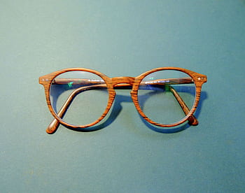 Close-up of fashionable wooden frame eyeglasses on a solid blue background. HD wallpaper