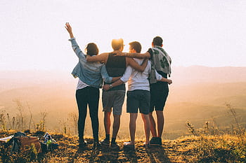 A group of friends embrace while enjoying a sunset view from the mountain top. HD wallpaper